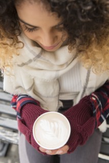 Mixed Race woman holding coffee cup with leaf in foam
