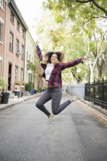 Mixed Race woman jumping for joy in city