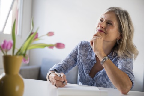 Pensive Caucasian woman writing on notepad