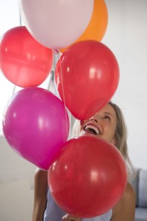 Smiling Caucasian woman holding multicolor helium balloons