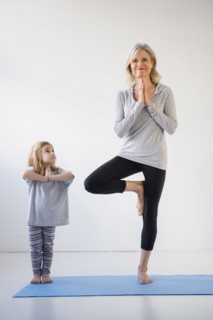 Caucasian granddaughter watching grandmother practicing yoga
