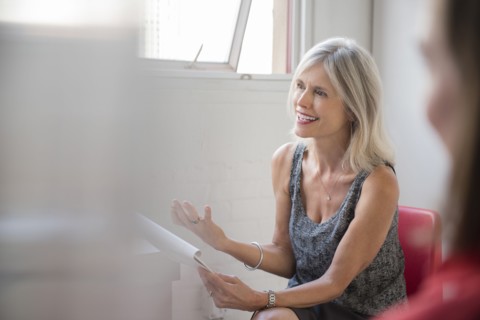 Gesturing Caucasian businesswoman with notepad talking in meeting
