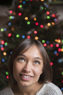 Pensive Mixed Race woman near Christmas tree
