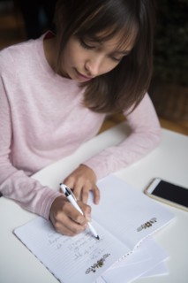 Mixed Race woman writing list in notepad