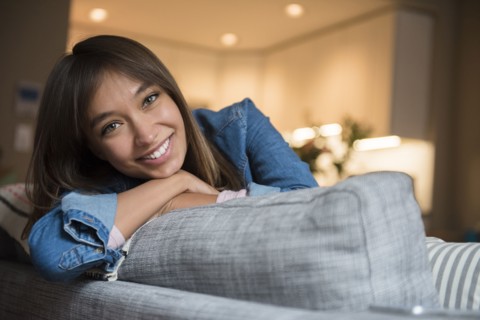 Smiling Mixed Race woman leaning on sofa