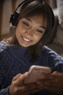 Mixed Race woman listening to cell phone with headphones