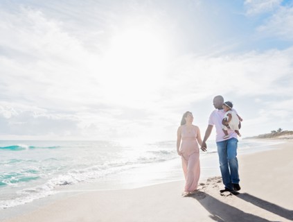 Couple walking on beach with baby daughter