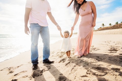 Couple holding hands of baby daughter walking on beach