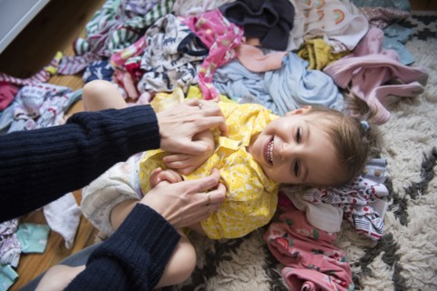 Hands of Caucasian mother tickling baby daughter on floor
