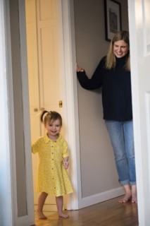 Mother watching Caucasian baby daughter standing in doorway