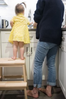 Caucasian baby girl helping mother washing dishes