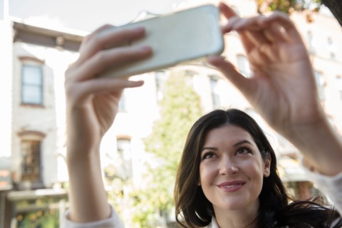 Smiling Caucasian woman posing for cell phone selfie