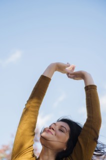 Wind blowing hair of Caucasian woman with arms raised