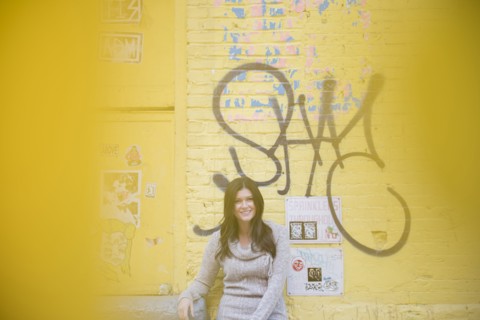 Caucasian woman leaning on yellow graffiti wall