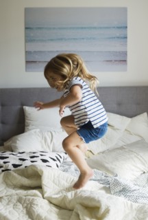 Caucasian girl jumping on bed