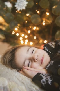 Caucasian girl sleeping near Christmas tree