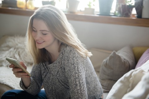 Smiling woman texting on cell phone
