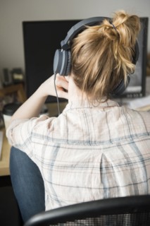 Woman using computer and listening to headphones