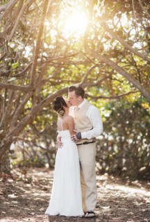 Caucasian bride and groom kissing under trees