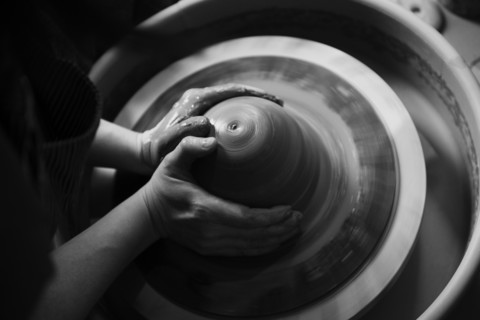 Hands of Caucasian woman shaping pottery clay on wheel