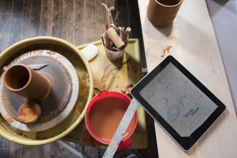 Cup and tools on pottery wheel near digital tablet