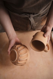 Hand of Caucasian woman holding pottery cup and bowl