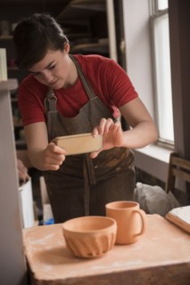 Caucasian woman photographing pottery with cell phone