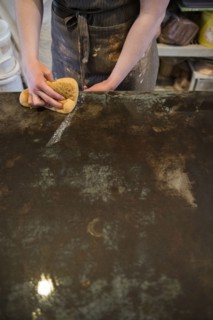 Caucasian woman wiping workshop table with wet sponge