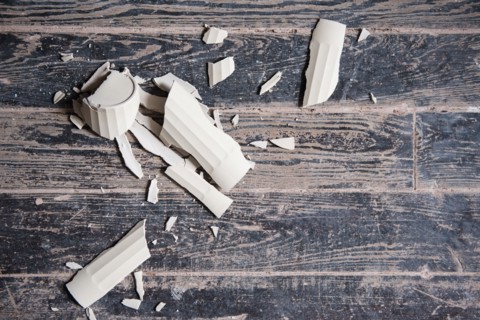 Broken shards of cup on wooden floor