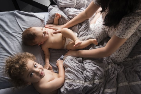 Caucasian mother playing with sons in bed
