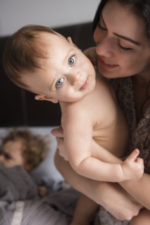 Caucasian mother holding baby son in bed