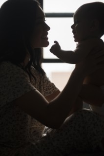 Silhouette of Caucasian mother holding baby son