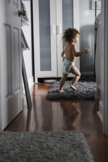 Caucasian boy wearing diaper running in corridor