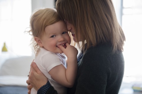 Caucasian mother holding smiling daughter