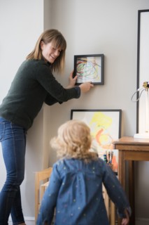Caucasian mother and daughter hanging painting on wall