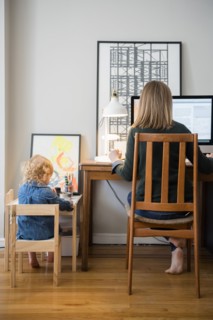 Caucasian mother working and daughter playing in home office