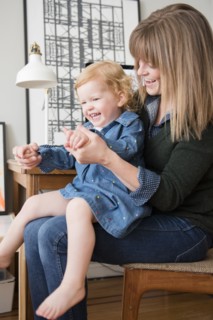 Caucasian mother playing with daughter sitting in lap