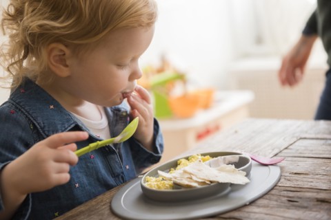 Caucasian girl eating with fingers and spoon