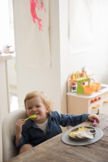 Caucasian girl eating with fork and spoon