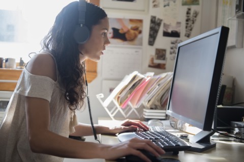 Hispanic woman listening to computer with headphones