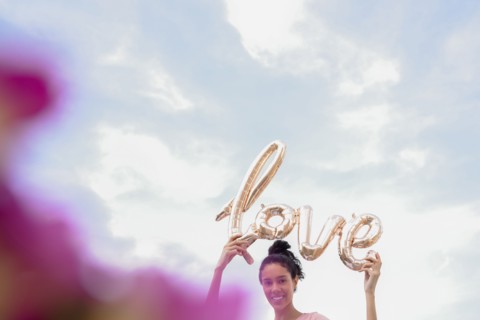 Hispanic woman holding love balloon outdoors
