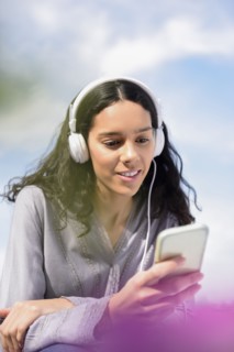 Hispanic woman listening to cell phone with headphones