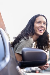 Hispanic woman leaning out car window