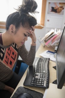 Frustrated Mixed Race woman sitting at desk using computer