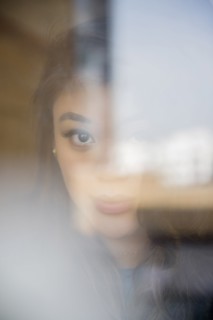 Face of serious Mixed Race woman behind window