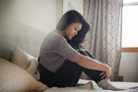 Depressed Mixed Race woman sitting on bed