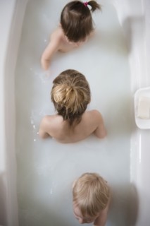 Caucasian boy and girls sitting in bathtub