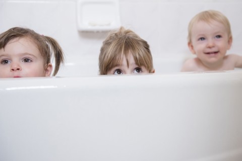 Caucasian boy and girls peaking from bathtub