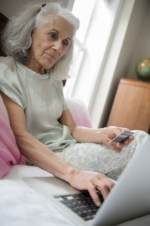Older woman shopping online with credit card and laptop