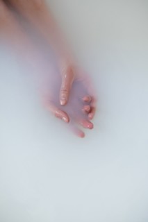 Hands of Caucasian woman in milk bath